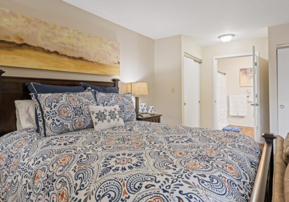 A bedroom with a blue and orange comforter at the Gallery at Markham House.