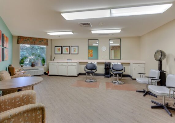 Markham House hair salon with two stations, chairs in waiting area, tables, and a window.